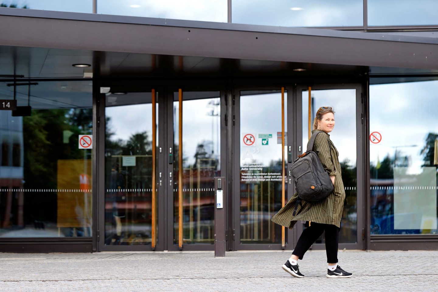 Elisa Lähde Aalto-yliopiston ulko-ovien edessä.
