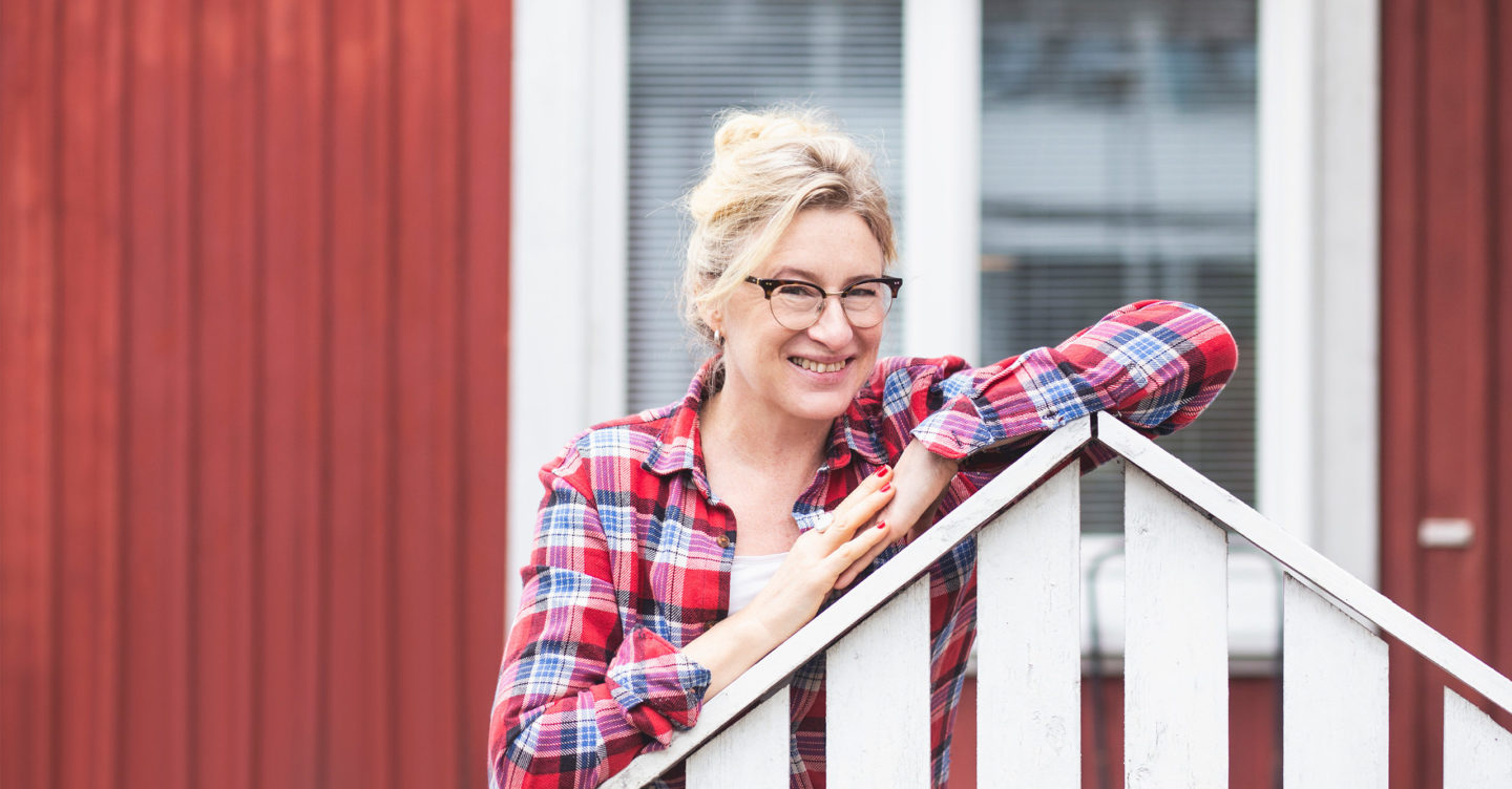 Katja Ståhl punaisen talon edustalla.