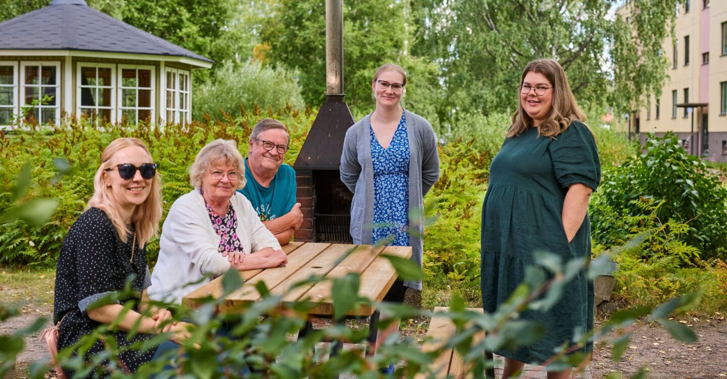 Naapurit yhdessä pihan pöydän ympärillä.